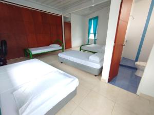 a bedroom with two beds and a toilet at Hotel Camino al Llano in Villavicencio