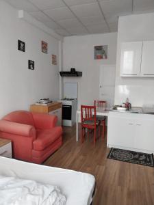 a living room with a red couch and a kitchen at Studio N2 Rez De Chaussée in Néris-les-Bains