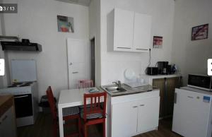 a small kitchen with white cabinets and a sink at Studio N2 Rez De Chaussée in Néris-les-Bains