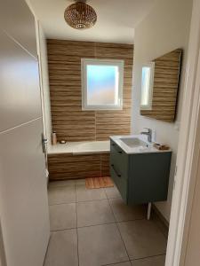 居让梅斯特拉Maison familiale piscine 3 chambres Gujan-Mestras !的带浴缸和水槽的浴室