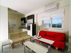 Una sala de estar con un sofá rojo y una cocina. en Holiday Residence Rodanthi, Darmarochori, en Darmarochori