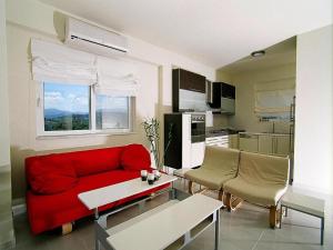 Una sala de estar con un sofá rojo y una cocina. en Holiday Residence Rodanthi, Darmarochori, en Darmarochori