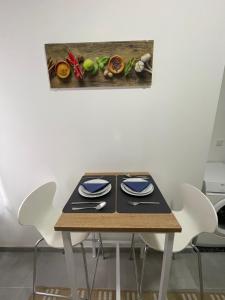 ein Tisch mit weißen Stühlen und einem blauen Teller in der Unterkunft Danisman Apartments 3 Zentral - Smart - Modern in Saarbrücken + 4 Fotos