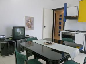 Zimmer mit einem Tisch und Stühlen sowie einem TV in der Unterkunft Casa Martina in Marina di Ragusa