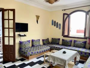 a living room with a couch and a table at Soleado apartamento al lado de la preciosa medina , a 3 minutos de la playa andando in Asilah