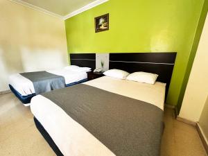 two beds in a hotel room with green walls at HOTEL 2 Mares PANAMA in Panama City +55 photos