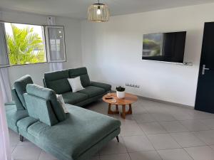 a living room with two green couches and a table at Nomade Evasion - Escale Paisible in Petit-Bourg