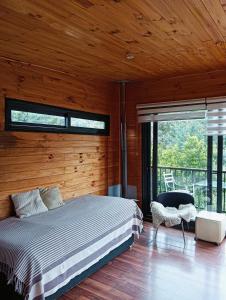 Un dormitorio con una cama y una ventana grande en Refugio Silvestre Parque Nacional Siete Tazas-Salida a río y pesca, en El Bolsico