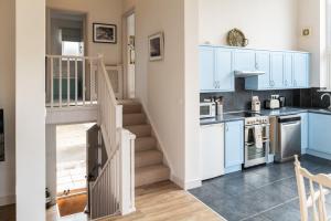 una cucina con armadi blu e una scala di Blueberry Barn, light and airy barn conversion near Bruton a Bruton Altre 19 foto