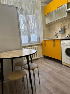a kitchen with a table and some yellow cabinets at Luxe-apartments 2х in Taraz