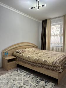 a bedroom with a large bed and a window at Luxe-apartments 2х in Taraz