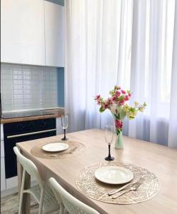 einem Esstisch mit 2 Platten und einer Vase aus Blumen in der Unterkunft Business class apartment EXPO in Astana