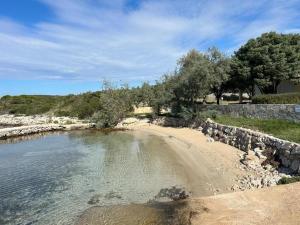 a beach with a rock wall and a body of water at House Sunshine in Mrljane