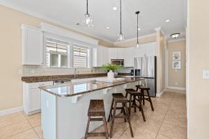 a kitchen with white cabinets and bar stools at Seeking Sunsets 30A in Rosemary Beach