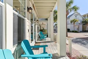 a porch with blue chairs on a house at Seeking Sunsets 30A in Rosemary Beach