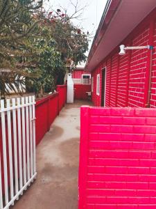 a red brick building with a white fence at Le case Rosse in Itapoa