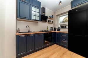 cocina con armarios azules y nevera negra en Cosy Apartment Połczyńska 6, en Bydgoszcz 14 fotos más