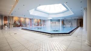 a large swimming pool in a building with a skylight at Seeschlößchen - Hotel Strandperle in Cuxhaven