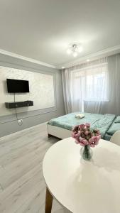 a living room with a table and a bed and a room with a couch at Apartment Lux, near EXPO in Astana