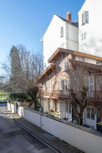 an old wooden house next to a white building at Résidence Serbie - Appartements design et climatisés en centre ville in Vichy