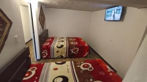 two beds in a small room with a television at Depa en el Centro in Tulancingo