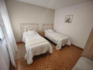 two beds in a room with white walls at Casa Marga O Grove in O Grove