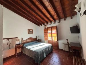 a bedroom with a bed and a desk and a television at Casa Rural Del Rio in Alozaina