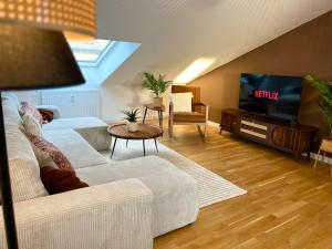 a living room with a white couch and a tv at 2-Zimmer Apartment - Zentral über den Dächern von Aschaffenburg - 5 min vom HBF - Gegenüber City Galerie in Aschaffenburg
