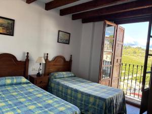 a bedroom with two beds and a sliding glass door at Casa Rural Del Rio in Alozaina +17 photos