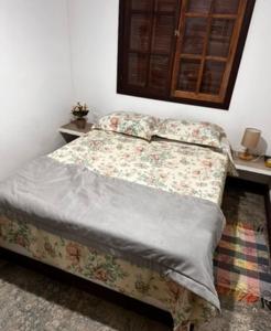 Cama en habitación con mesa y colcha en Aconchego da Cachoeira, en Paraty