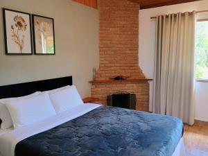 a bedroom with a large bed and a fireplace at Chalé Recanto in Visconde De Maua