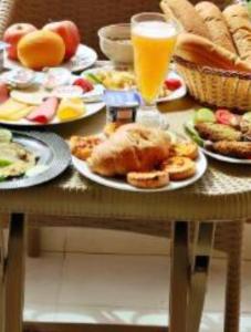 a table with plates of food and a glass of orange juice at Pyramids Heritage suites in Ghaţāţī
