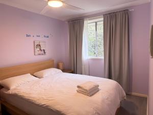 キャンベラにあるScullin 3BR Houseのベッドとタオル2枚のある寝室