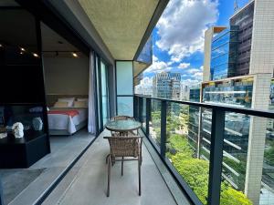 a room with a balcony with a bed and a table at VN Millennium Faria Lima in São Paulo