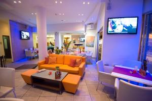 un restaurante con sofás, mesas y TV en la pared en Eligonia Hotel Apartments, en Ayia Napa