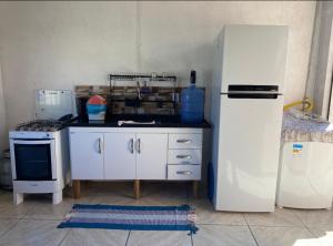 a kitchen with a white refrigerator and a stove at Casa da Cris em Praia do Grauçá com Wi-Fi, ar condicionado e garagem in Caravelas