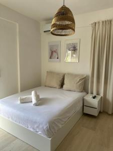 a bedroom with a large white bed with a pendant at I&L Apartments in Asprovalta