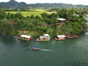 a boat traveling down a river with several houses at Vangngo View Resort, Muang Fuang in Muang Fuang