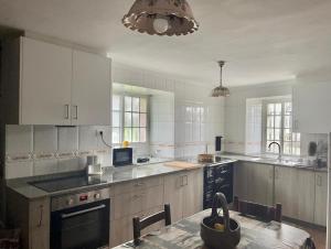 a kitchen with white cabinets and a black appliance at Rincón rural in Tomonde
