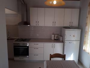 a kitchen with white cabinets and a white refrigerator at House Vrisnik in Jelsa