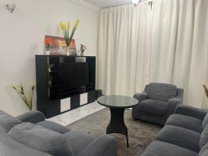a living room with two chairs and a table and a tv at Ajman Oasis 29 in Ajman 