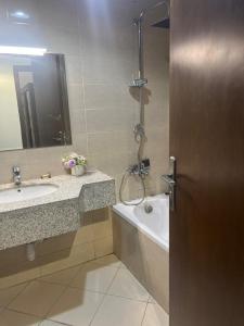 a bathroom with a tub and a sink and a shower at Ajman Oasis 29 in Ajman 