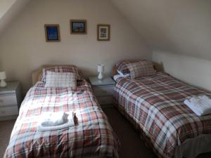 a bedroom with two beds with a cat laying on them at Cranstakie Cottage in Durness