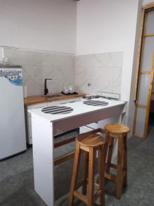 a kitchen with a stove and two wooden stools at Casa Silvia in Bahía Blanca +4 photos