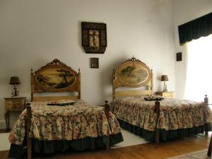um quarto com duas camas e um relógio na parede em Solar das Avencas em Portalegre