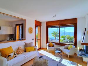 a living room with a white couch and two chairs at House in Luino with Green Garden and City Views in Luino