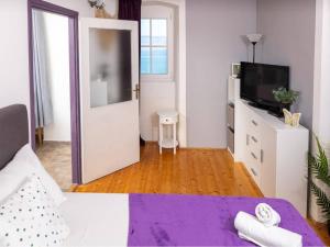 a room with a bed and a tv and a door at Apartments Vela Stiniva - Two Bedroom Apartment with Sea View and Terrace in Zastražišće +2 photos