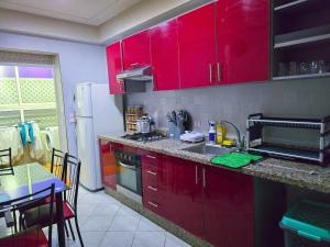 a kitchen with red cabinets and a table with a dining room at Spacious & chic - 3 min from Casa City Finance " CFC " in Casablanca