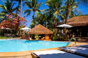 a swimming pool with palm trees and a resort at Pousada Berro do Jeguy in Pipa