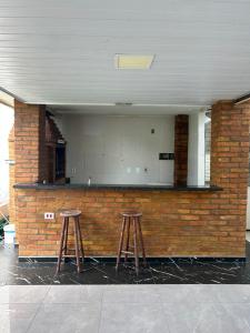 two bar stools in front of a brick wall at Chácara das Oliveiras in Campinas